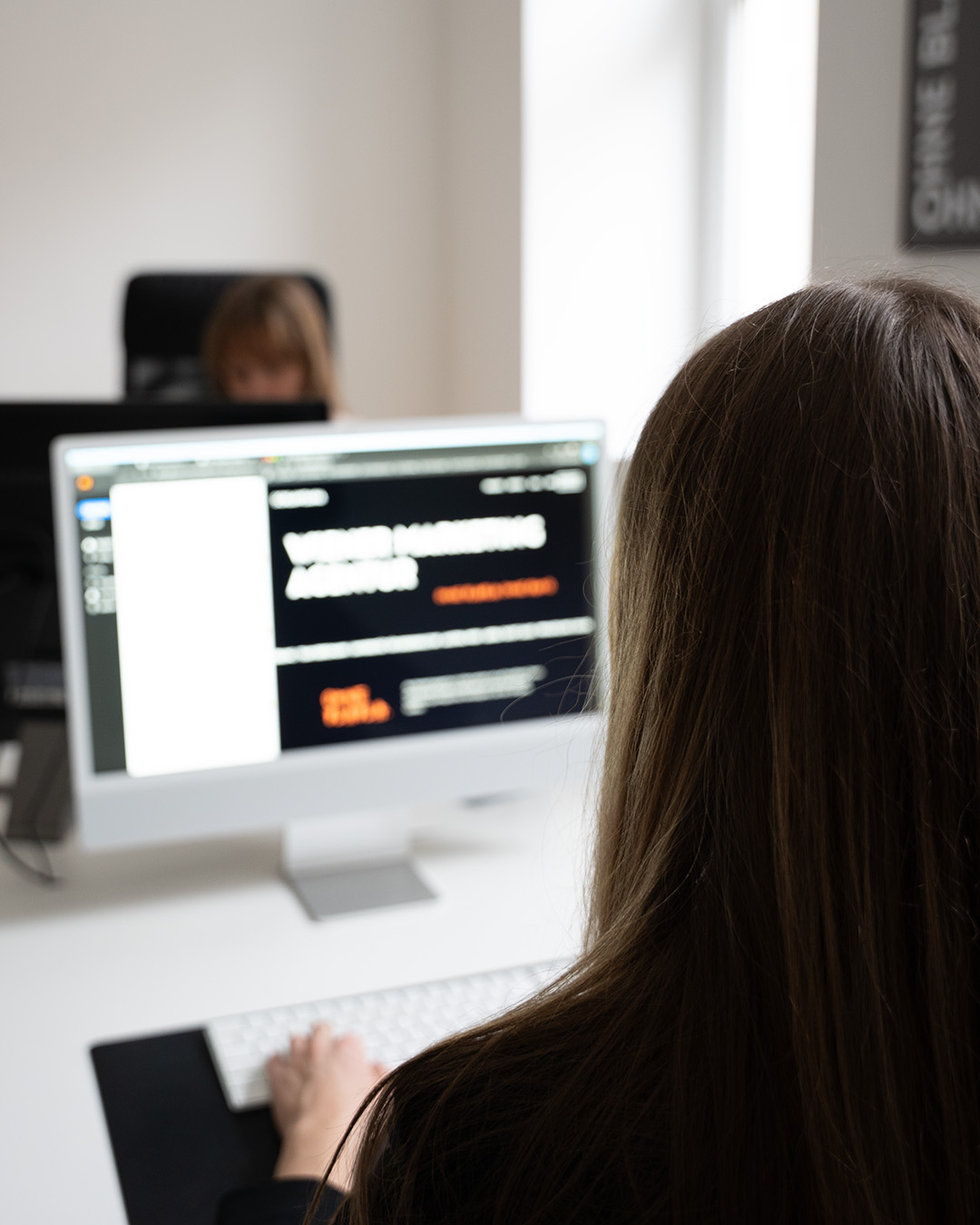 Frau sitzt vor einem iMac und arbeitet an einer barrierefreien Webseite