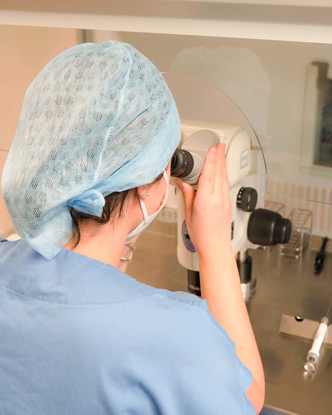 Bild einer Labormitarbeiterin in einer Privatklinik, die in ein Mikroskop blickt. Ein Bild aus dem Klinikmarketing Projekt von SCHLAWEANA
